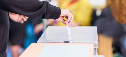 Hand placing a card in a ballot box
